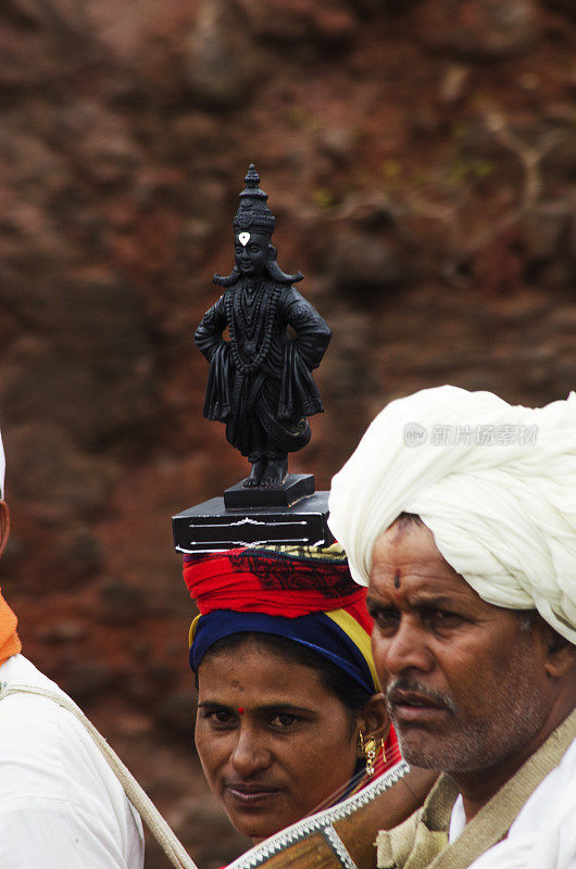 varkari女士和Vitthala神像的肖像。dnyaneshwar palkhi朝圣——一名妇女与其他朝圣者一起头顶神像在印度浦那，马哈拉施特拉邦
